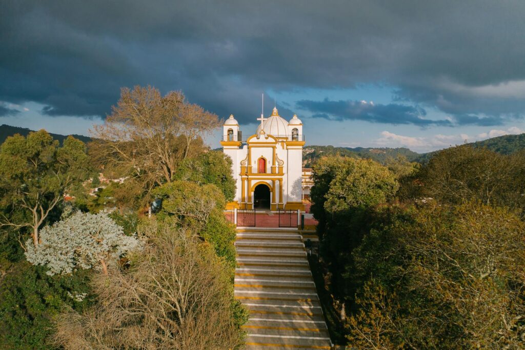 Aerial view of a picturesque chapel surrounded by lush greenery in San Cristóbal de las Casas, Mexico.